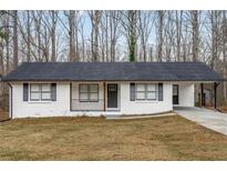 Charming single-story home with a brick exterior, a black roof and shutters and a covered carport at 365 Cowan Rd, Covington, GA 30016