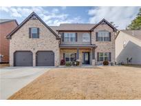 Charming two-story brick home with a well-manicured lawn, two-car garage, and inviting front porch at 1217 Trophy Club Ave, Dacula, GA 30019