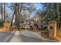 Brick home showcasing a circular driveway, manicured landscaping, and mature trees providing a serene and private setting at 8185 Habersham Waters Rd, Atlanta, GA 30350