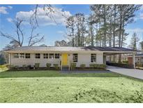Charming brick home featuring a well-manicured lawn, attached carport, and inviting yellow front door at 1963 Shepherd Sw Cir, Atlanta, GA 30311