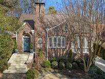 Charming brick home featuring a blue arched front door, beautiful landscaping, and leaded glass windows at 549 Lakeshore Ne Dr, Atlanta, GA 30307