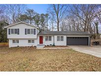 Charming split-level home featuring a red front door, gray garage, and manicured lawn at 545 Birch Ln, Lawrenceville, GA 30044