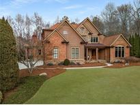 Inviting brick and wood home with manicured front lawn and mature trees at 5497 Aviemore Ct, Suwanee, GA 30024