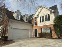 Two-story home with brick and white siding, a two-car garage, black shutters, and a well-maintained front yard at 3565 Mystic Dr, Buford, GA 30519