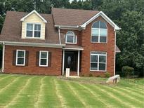 Charming two-story brick home featuring a well-manicured lawn, updated windows, and inviting front entrance at 1931 Harvest Way, Loganville, GA 30052