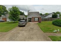 Charming single-story house with brick accents, a well-manicured lawn, and a long concrete driveway at 1972 Brittania Cir, Woodstock, GA 30188