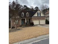 Charming brick home with a well-manicured lawn, mature trees, and a two-car garage at 1045 Legacy Walk, Woodstock, GA 30189