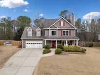 Charming two-story home with red shutters, a well-manicured lawn, and a driveway leading to an attached two-car garage at 128 Holly Pl, Canton, GA 30115