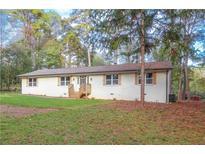 Charming single-story home with a white brick exterior, complemented by a well-manicured front yard and mature trees at 380 Inman Rd, Fayetteville, GA 30215