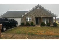Charming single-story home with stone accents, a well-maintained yard, and an attached garage at 10936 Station Dr, Hampton, GA 30228