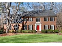 Traditional brick home featuring a manicured lawn, a red front door, and symmetrical window design at 2170 Azalea Dr, Roswell, GA 30075
