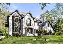 Stately two-story brick home boasts an arched entryway, manicured lawn, and mature trees in a desirable neighborhood at 880 Cold Harbor Dr, Roswell, GA 30075