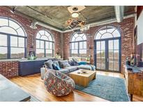 Expansive living room featuring exposed brick, hardwood floors, and large arched windows at 3235 Roswell Ne Rd # 919, Atlanta, GA 30305