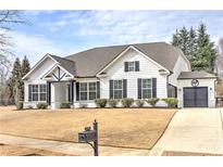 Charming white exterior with black shutters, covered porch, and attached two-car garage at 608 Trotter Way, Canton, GA 30115