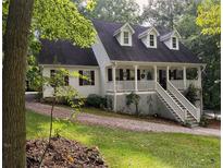 Charming two-story home featuring a welcoming front porch with dormer windows and landscaped surroundings at 525 S Lost Lake Cv, Villa Rica, GA 30180