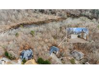 Aerial view of a wooded lot with a lake and a home inset showcasing exterior features at 4420 Little Falls Dr, Cumming, GA 30041