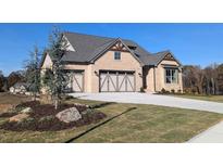Craftsman-style home featuring a three-car garage, brick facade, and manicured front lawn at 2235 Windsor Bluffs Dr, Cumming, GA 30041