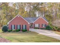 Charming one-story red brick home featuring a well-manicured lawn, classic black shutters, and a welcoming driveway at 868 Clarion Way, Lawrenceville, GA 30044