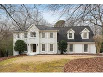 Charming two-story home with a white brick facade, dormer windows, and mature trees at 295 Bruton Way, Atlanta, GA 30342