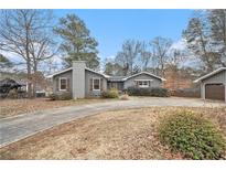 Charming single-story home with gray siding, brick chimney, and a circular driveway at 185 Nickajack Se Rd, Mableton, GA 30126