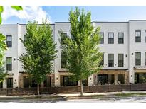 Inviting townhome featuring white brick, lush trees, modern design and a charming fenced front yard at 1855 La Dawn Nw Ln, Atlanta, GA 30318