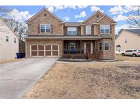 Charming two-story brick home with a welcoming front porch and well-maintained front yard on a sunny day at 6124 Locklear Way, Douglasville, GA 30134