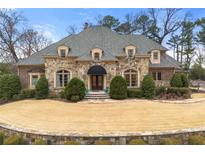 Stately stone home with manicured lawn and inviting entrance, perfect for luxurious living at 4266 Woodland Brook Se Dr, Atlanta, GA 30339