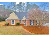 Charming brick home with a landscaped front yard, beautiful lawn, and mature trees at 221 The Esplanade Se Way, Loganville, GA 30052