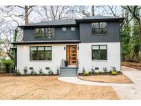 Stylish two-story home featuring a white brick facade, modern wood door, and well-manicured landscaping at 1788 Piper Se Cir, Atlanta, GA 30316