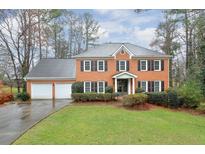 Brick home with a two-car garage, green lawn, and mature landscaping at 1849 Linnet Ne Ct, Roswell, GA 30075