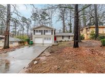 Split-level home with white brick, black shutters, two-car garage, and red front door at 2202 Troutdale Dr, Decatur, GA 30032