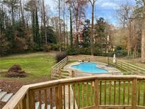 A backyard pool with a wooden fence and green grass on a sunny day at 805 Wesley Oak Rd, Atlanta, GA 30328