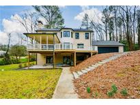 Expansive rear exterior featuring an elevated deck, patio, and stairs ascending towards the attached garage at 805 Wesley Oak Rd, Atlanta, GA 30328