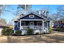Charming blue two-story home featuring a welcoming front porch, well-maintained landscaping, and a cozy aesthetic at 1659 Olympian Sw Way, Atlanta, GA 30310