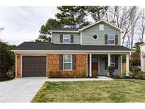 Charming two-story home with brick accents, a well-manicured lawn, and an attached garage at 6242 Marbut Farms Ln, Lithonia, GA 30058