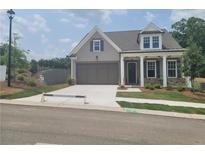 Charming home features a two-car garage, neutral siding, stone accents, and a well-manicured front lawn at 1209 Lakeside Overlook, Canton, GA 30114