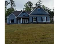 Charming single-Gathering home featuring blue siding, black shutters, a covered porch, and a well-manicured front lawn at 1130 Holly Dr, Loganville, GA 30052