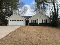 Charming single-story home with a well-maintained lawn, attached garage, and inviting entrance at 7008 Woodfield Way, Woodstock, GA 30188