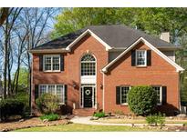 Charming two-story brick home with a welcoming front door, black shutters, and lush green lawn at 6435 Ivey Creek Cir, Cumming, GA 30040