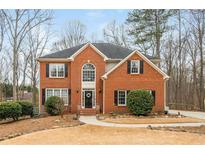 Charming two-story red brick home featuring a black roof, landscaped yard, and welcoming front entrance at 6435 Ivey Creek Cir, Cumming, GA 30040