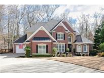 Beautiful brick home with a well-manicured lawn and mature trees on a sunny day at 5390 Owl Creek Nw Pointe, Powder Springs, GA 30127