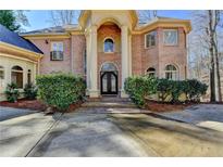 Stunning brick home with an arched entryway and iron door design, adding elegance and curb appeal at 150 Stone Pond Ln, Johns Creek, GA 30022