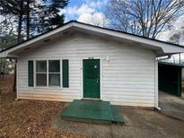 Charming single-story home with a green door and window shutters and an attached carport at 3118 Rockbridge Road Southwest, Avondale Estates, GA 30002