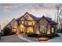 Stately stone and stucco home featuring a well-manicured lawn and elegant architectural details at 6955 Laurel Oak Dr, Suwanee, GA 30024