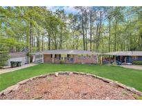 Charming brick home with a lush green front yard, complemented by a landscape rock border and mature trees at 2493 Woodacres Ne Rd, Atlanta, GA 30345