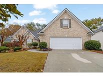 Charming brick home featuring a two-car garage, manicured lawn, and mature landscaping at 777 Glen Valley Way, Dacula, GA 30019