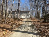 Two-story home with a long driveway leading to an attached two-car garage surrounded by trees at 5080 Springtree Ct, Lithonia, GA 30038