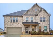 Beautiful two-story home featuring stone accents, brick, a covered porch, and an attached two-car garage at 938 Blue Juniper Cir, Loganville, GA 30052