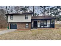 Charming home featuring a two-car garage, brick accents, and a covered porch at 5433 Rocky Pine Dr, Stonecrest, GA 30038