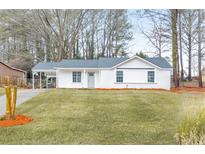 Charming single-story home with a well-manicured lawn, complemented by mature trees and a covered carport at 8453 Alden Dr, Riverdale, GA 30274